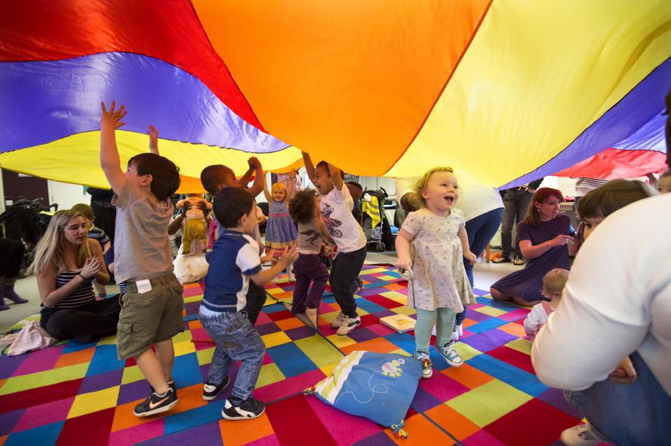 Children at a charity workshop under a colourful parachute
